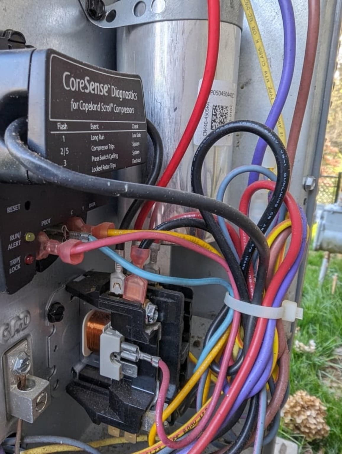 CoreSense diagnostics module and complex electrical wiring inside an outdoor air conditioning unit's control panel.